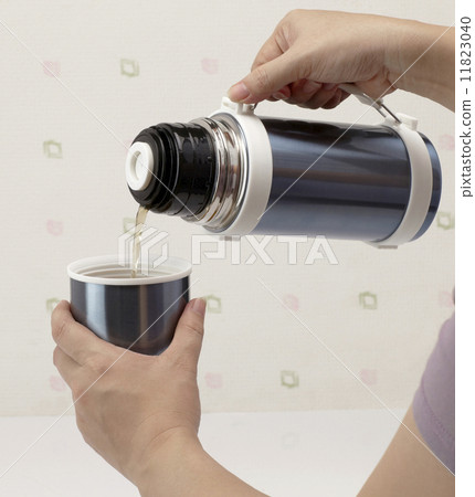 ouring hot tea from thermos into cup ouring hot tea from thermos into cup 11823040
