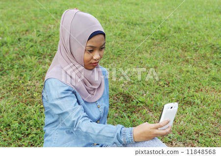 Asian girls watching mobile at park Asian girls watching mobile at park 11848568