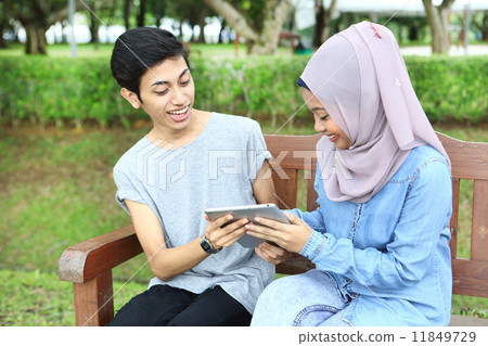 使用片劑的亞洲夫婦在公園 11849729