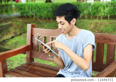 使用片劑的亞洲人在公園 11849731