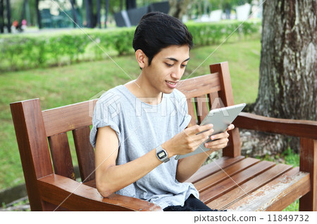 使用片劑的亞洲人在公園 11849732