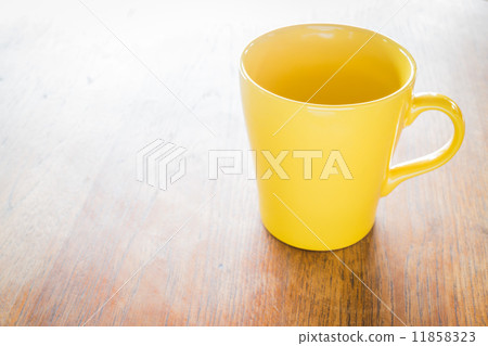 Yellow ceramic cup on wooden table 11858323