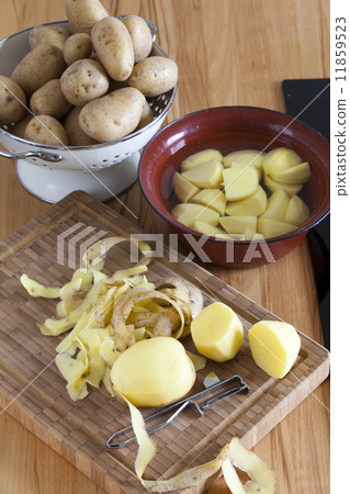 Raw potatoes and kitchen utensils on the worktop 11859523