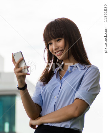 Beautiful Asian businesswoman text messaging outdoor 11861089