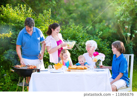Happy big family enjoying BBQ lunch with grandmother eating grilled meat in the garden 11866876
