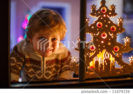 Smiling boy standing by window at Christmas time and holding can Smiling boy standing by window at Christmas time and holding can 11879156