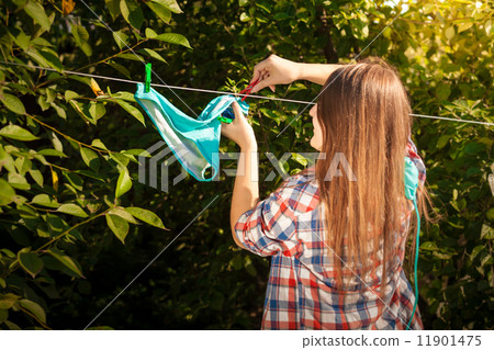woman in shirt drying bikini on clothesline woman in shirt drying bikini on clothesline 11901475