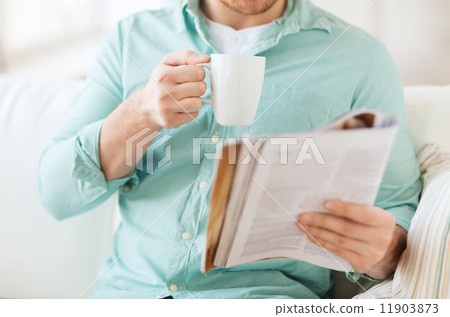close up of man with magazine drinking from cup 11903873