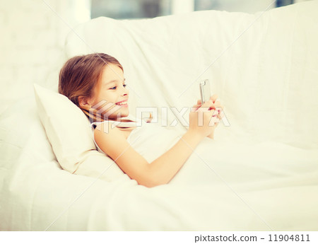 little girl with smartphone playing in bed 11904811