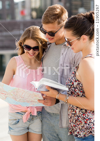 smiling friends with map and city guide outdoors smiling friends with map and city guide outdoors 11905267