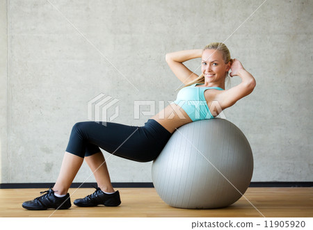 smiling woman with exercise ball in gym smiling woman with exercise ball in gym 11905920
