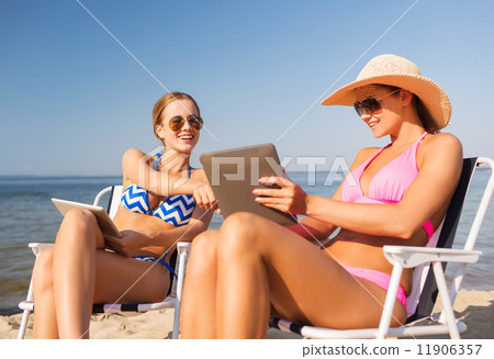 smiling women with tablets pc computers on beach smiling women with tablets pc computers on beach 11906357