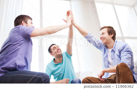 smiling male friends giving high five at home 11906362