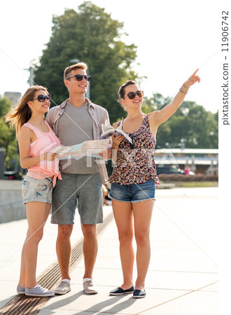 smiling friends with map and city guide outdoors smiling friends with map and city guide outdoors 11906742