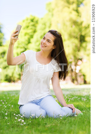 smiling young girl with smartphone sitting in park smiling young girl with smartphone sitting in park 11906929