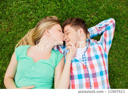 smiling couple lying on grass and kissing in park smiling couple lying on grass and kissing in park 11907421