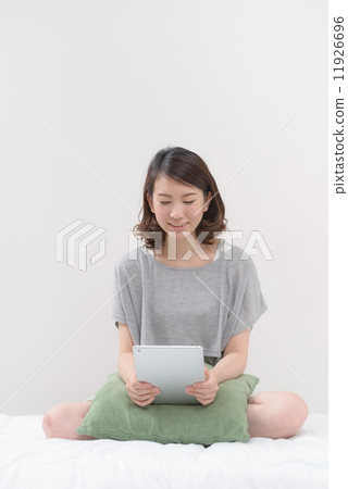 使用片劑個人計算機的一名婦女在床上 使用片劑個人計算機的一名婦女在床上 11926696