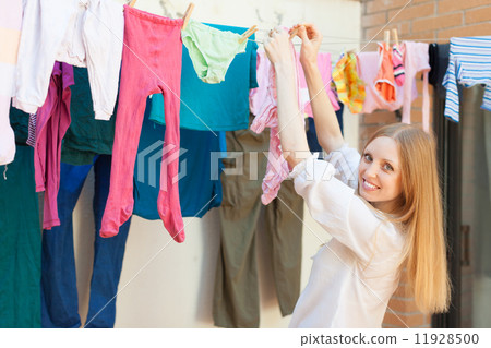 Positive long-haired girl drying clothes on clothes-line Positive long-haired girl drying clothes on clothes-line 11928500
