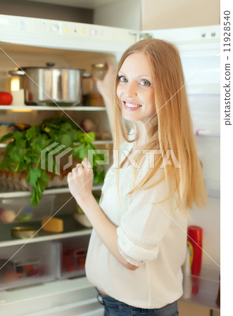 Positive woman looking for something in refrigerator Positive woman looking for something in refrigerator 11928540