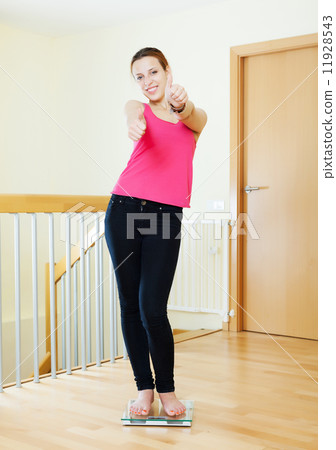 Happy girl standing on bathroom scales Happy girl standing on bathroom scales 11928543