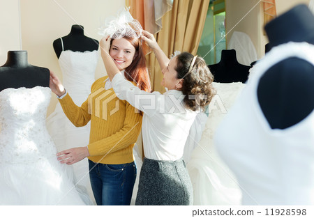 consultant helps girl chooses white bridal outfit 11928598