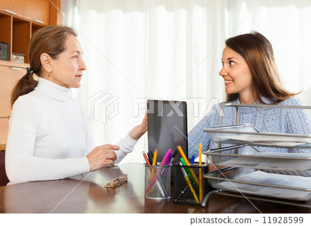 Mature woman answer questions of outreach worker with laptop Mature woman answer questions of outreach worker with laptop 11928599