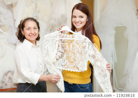 Happy mature bridesmaid with bride chooses bridal clothes Happy mature bridesmaid with bride chooses bridal clothes 11928618