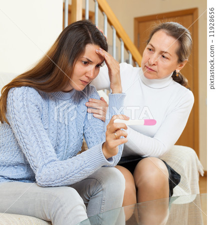 woman consoling the sad daughter with pregnancy test 11928656