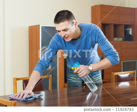 guy dusting wooden table with rag and cleanser at home guy dusting wooden table with rag and cleanser at home 11928783