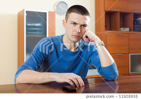 Ordinary guy with phone at table Ordinary guy with phone at table 11928938