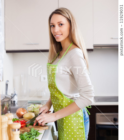 Happy woman in apron slicing vegetables 11929031
