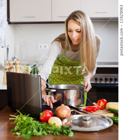 woman looking in laptop during cooking soup woman looking in laptop during cooking soup 11929063