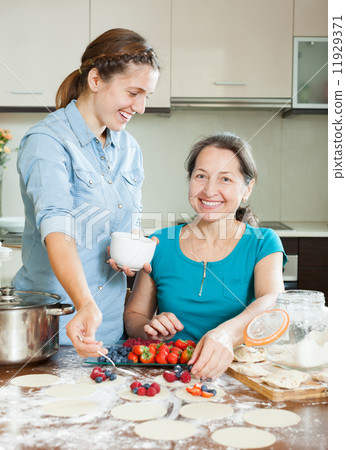 Two women making sweet vareniki with berries Two women making sweet vareniki with berries 11929371