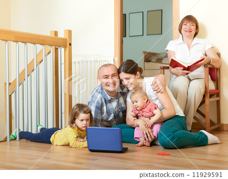 Happy family of three generations using blue laptop in home int 11929591