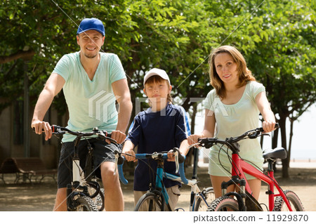 Happy family of three cycling through city 11929870