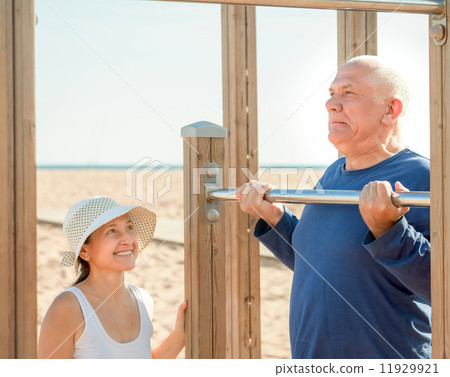 Happy senior couple training on pull-up bar Happy senior couple training on pull-up bar 11929921