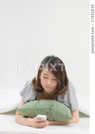 A woman using a smartphone in bed 11932616