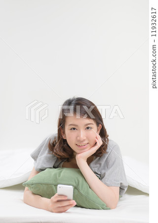 A woman using a smartphone in bed 11932617