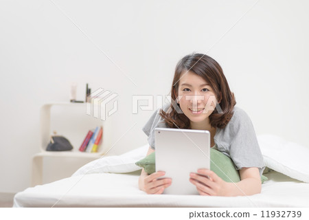 使用片劑終端的婦女在床上 11932739