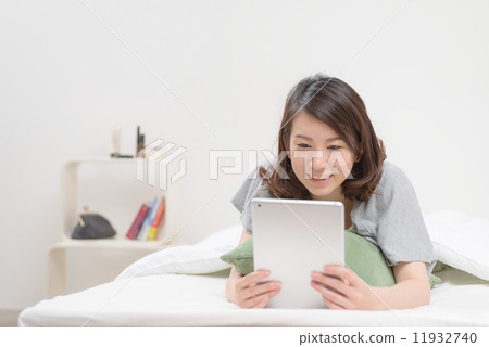 使用片劑終端的婦女在床上 11932740