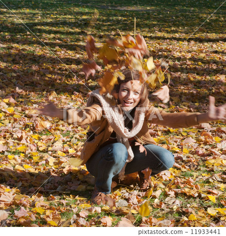 Woman drop leaves in autumn park 11933441