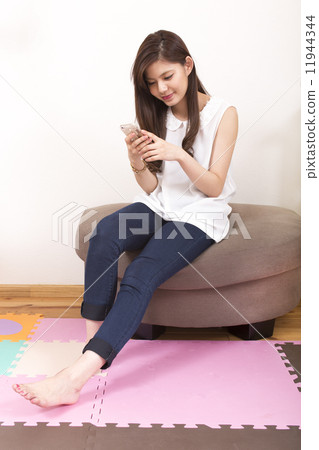 A young woman sitting on the sofa to see the cell phone A young woman sitting on the sofa to see the cell phone 11944344