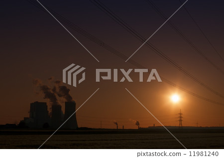 Brown coal power plant with cooling towers and steam and powerlines during sunset with red sky 11981240