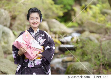 在手中戴著日本庭院和禮物的中間婦女 在手中戴著日本庭院和禮物的中間婦女 11991658