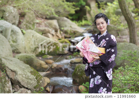 在手中戴著日本庭院和禮物的中間婦女 在手中戴著日本庭院和禮物的中間婦女 11991660