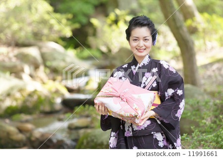 在手中戴著日本庭院和禮物的中間婦女 在手中戴著日本庭院和禮物的中間婦女 11991661