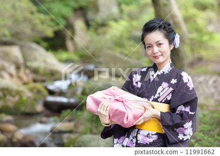在手中戴著日本庭院和禮物的中間婦女 在手中戴著日本庭院和禮物的中間婦女 11991662