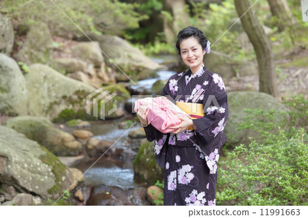 在手中戴著日本庭院和禮物的中間婦女 在手中戴著日本庭院和禮物的中間婦女 11991663