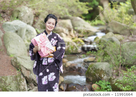 在手中戴著日本庭院和禮物的中間婦女 在手中戴著日本庭院和禮物的中間婦女 11991664