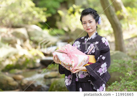 在手中戴著日本庭院和禮物的中間婦女 11991665